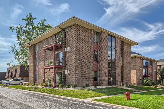 Front view of a multi-story brick apartment building with balconies.