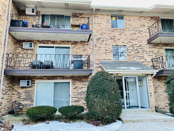Front view of a multi-story residential building with brick exterior and balconies.