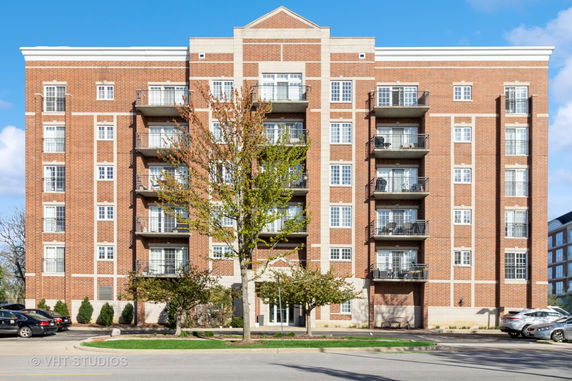 Front view of a multi-story apartment building with brick exterior and balconies.