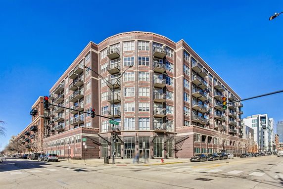 Front view of a multi-story apartment building on a city street corner.