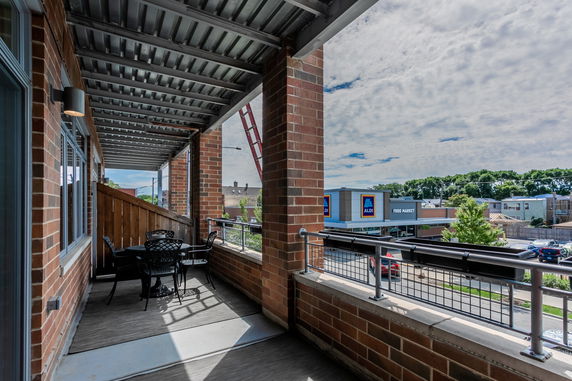 Covered balcony with a view of surrounding buildings and a food market.