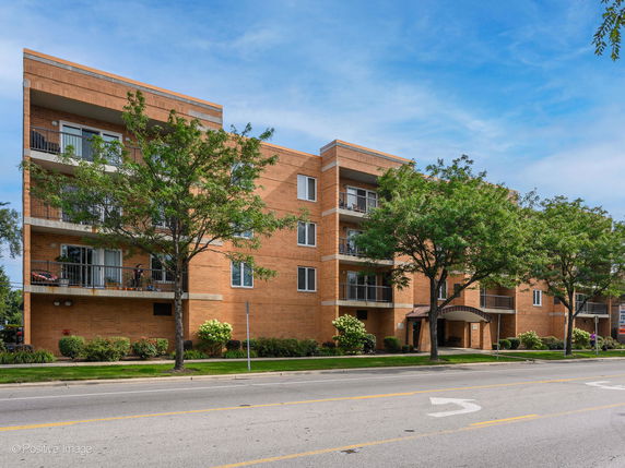 Front view of a multi-story brick apartment building with balconies.