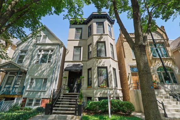 Front view of a multi-story house with a staircase and bay windows.