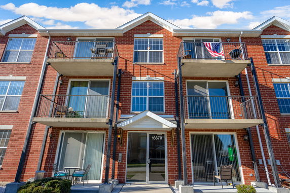 Front view of a multi-story brick building with balconies and sliding glass doors.