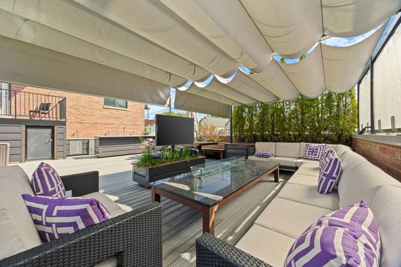 Rooftop patio with seating area, canopy shade, and outdoor furniture.