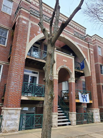 Front view of a multi-story brick apartment building with balconies.