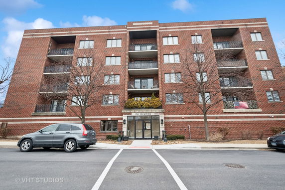 Front view of a multi-story brick apartment building with balconies.