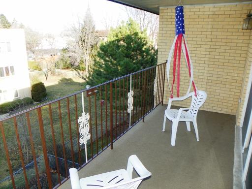 View from a balcony with chairs overlooking a green area with trees.
