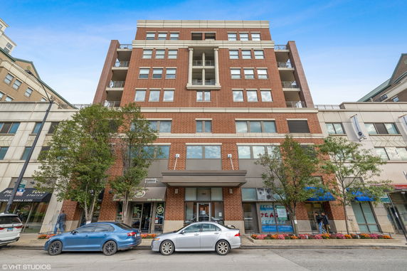 Front view of a multi-story brick building with balconies and large windows.