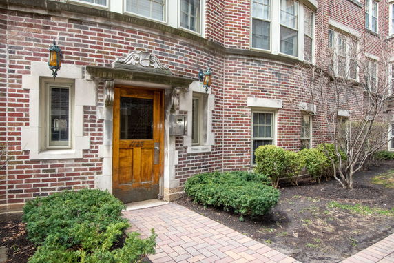 Front view of a brick building with wooden door and adjacent windows.