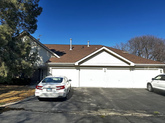 Front view of a house with a double garage and parked cars.
