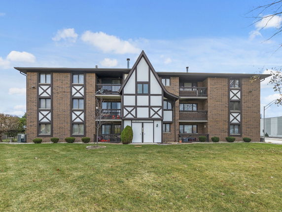 Front view of a multi-story apartment building with brown brick and white accents.