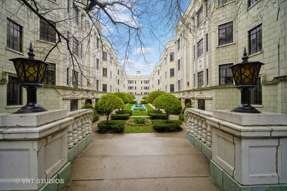 Front view of an elegant, multi-story building with a central courtyard and decorative lamps.