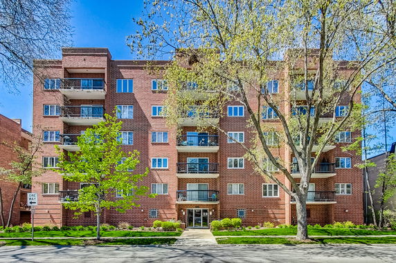 Front view of a multi-story brick apartment building with balconies.