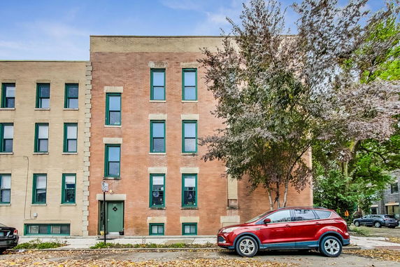 Front view of a multi-story brick building with green window frames.