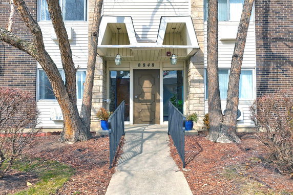 Front entrance of a multi-story building with pathway and trees.