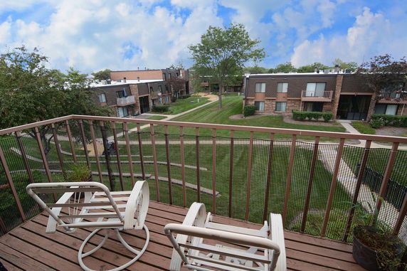 Panoramic view from a balcony overlooking apartment buildings and a landscaped garden area.