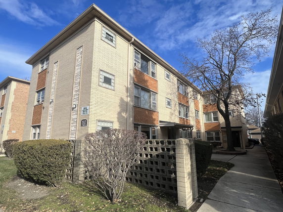 Front view of a multi-story apartment building with brick facade.