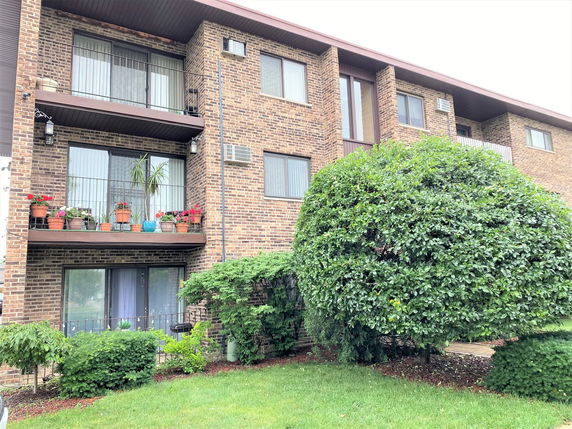 Front view of a brick apartment building with balconies.