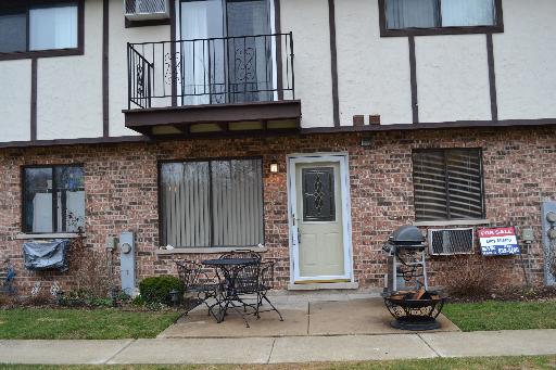 Front view of a two-story brick house with a balcony and a patio area.