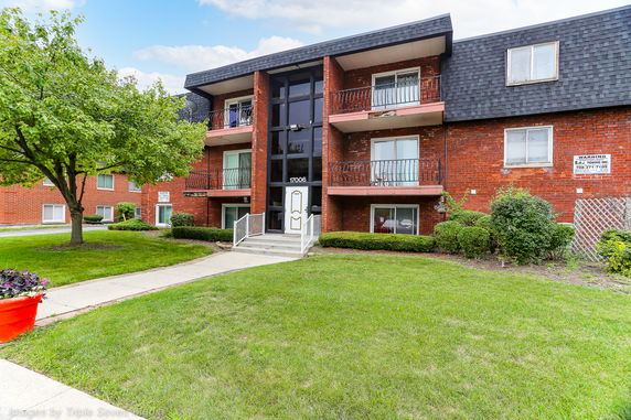 Front view of a multi-story brick apartment building with balconies.