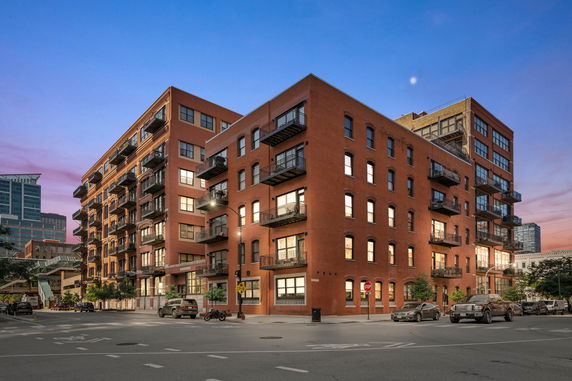 Front view of a multi-story brick apartment building with balconies.