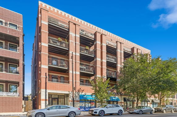 Front view of a multi-story brick apartment building with balconies.
