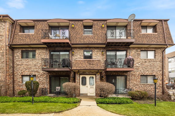 Front view of a multi-story brick apartment building with balconies.