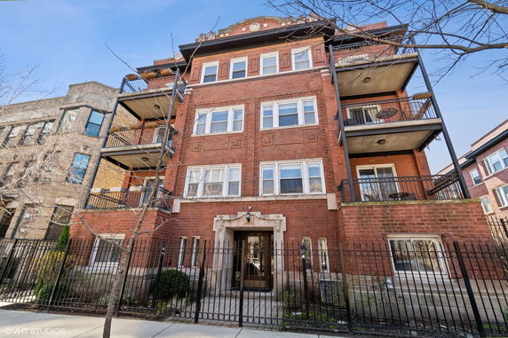 Front view of a multi-story brick apartment building with balconies.