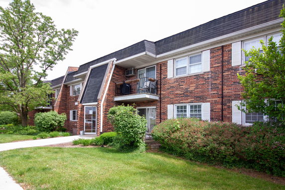 Front view of a two-story brick building with balconies and white window shutters.