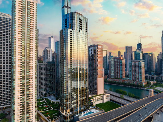 Front view of a modern high-rise building with glass facade in a cityscape.