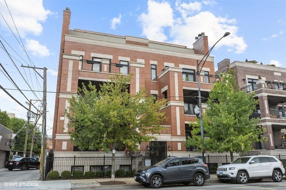 Front view of a multi-story brick apartment building with balconies.