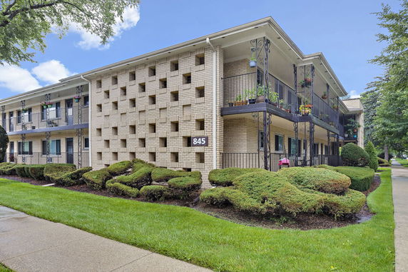 Front view of a multi-story apartment building with unique brick pattern and balconies.