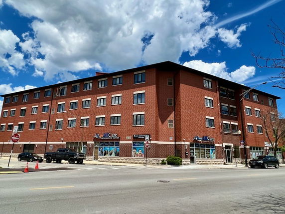 Front view of a multi-story brick building with commercial spaces on the ground floor.