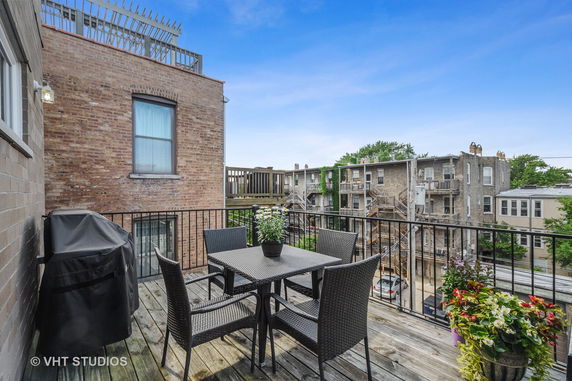 View from a balcony overlooking neighboring buildings and a parking area.