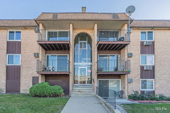 Front view of a multi-story apartment building with balconies and a central entrance.