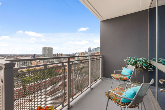 Balcony view of cityscape with outdoor seating and decorative flowers.