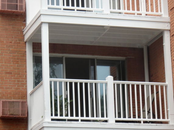 Close-up view of a building's exterior showing balconies with white railings and sliding glass doors.
