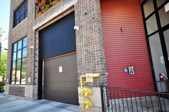 Front view of a brick building with large windows and a garage door.