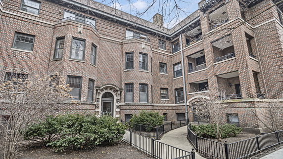 Front view of a brick apartment building with multiple levels and balconies.