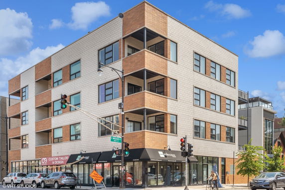 Front view of a modern four-story building with commercial spaces on the ground floor.