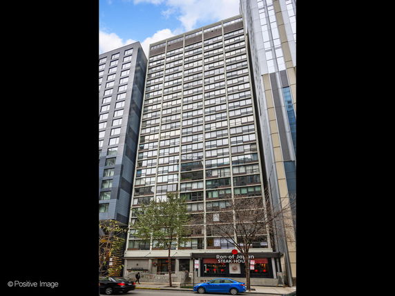 Front view of a tall urban building with a restaurant on the ground floor.