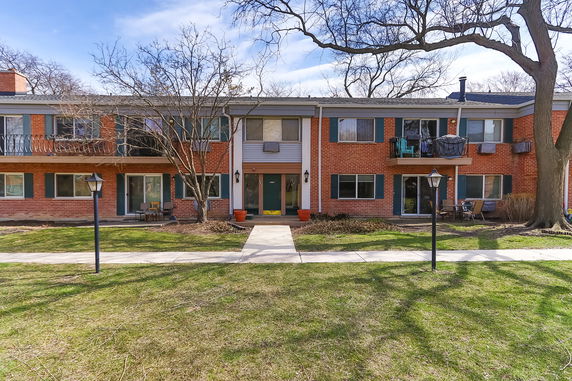 Front view of a two-story brick building with balconies and green shutters.