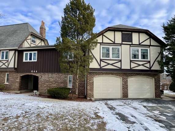 Front view of a two-story house with brick and Tudor-style facade with a double garage.