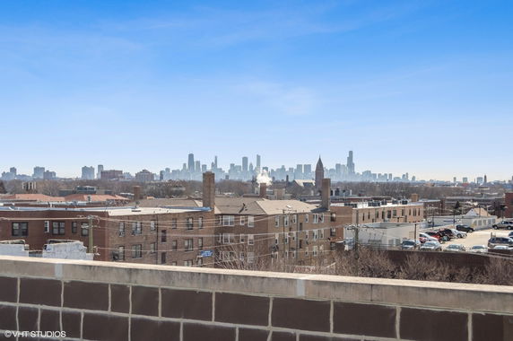 Panoramic view from a rooftop showing a city skyline in the background.