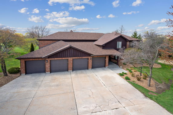 Front view of a two-story house with a three-car garage and brick exterior.