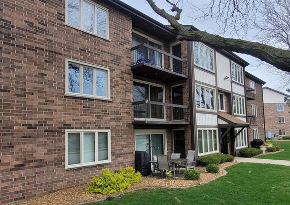 Front view of a multi-story brick apartment building with balconies.