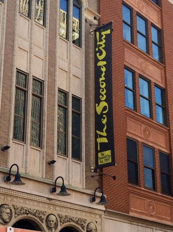 Front view of a multi-story building with architectural detailing and a large vertical sign.