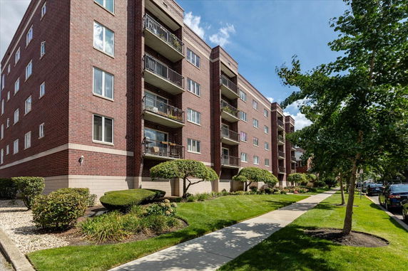 Front view of a multi-story brick apartment building with balconies.