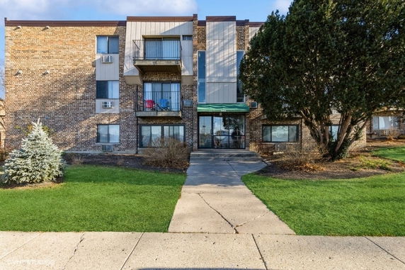 Front view of a multi-story residential building with balconies and entrance.